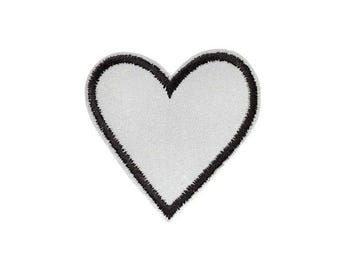 Op de afbeelding: Een hartvormige patch met een effen wit midden en een dikke, getextureerde zwart geborduurde rand. Het ontwerp is symmetrisch met een glad, plat oppervlak in het witte gedeelte en een verhoogde, gestikte rand van zwart garen.
