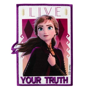 Op de afbeelding: Een geborduurde patch in paars en wit met een cartoon afbeelding van Anna uit Frozen II. De patch heeft de tekst "Live Your Truth" en een klein beeld van een tarwehalm.