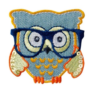 Op de afbeelding: Een blauwe uil met een bril met gele en oranje accenten. De uil heeft pailletten op zijn vleugels.