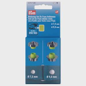 Könnte beinhalten: Ein Prym Werkzeug-Set für Hohlnieten. Die Verpackung ist blau und weiß, mit Text auf Deutsch, Englisch und Französisch. Das Set enthält Metallwerkzeuge mit grünen Einsätzen und die Verpackung weist Größen von 7,5 mm und 9,0 mm auf.