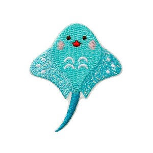 Puede incluir: Un parche bordado azul y blanco de una raya de dibujos animados con una cara sonriente. La raya tiene la barriga blanca y la cola azul.