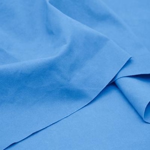 Könnte beinhalten: Nahaufnahme eines hellblauen Stoffes mit sichtbarer Textur und Falten. Der Stoff scheint ein gewebtes Material zu sein, möglicherweise Baumwolle oder Leinen, mit einem weichen, matten Finish. Die Farbe ist ein lebendiges, einfarbiges Hellblau.