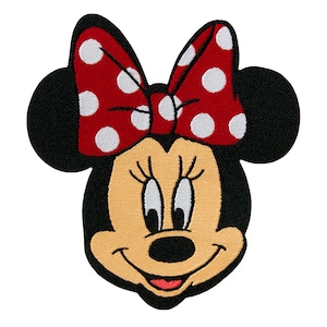 Op de afbeelding: Een rode strik met witte stippen zit bovenop een geborduurd zwart-wit cartoonbeeld van Minnie Mouse. De afbeelding is een close-up van haar gezicht met een brede glimlach.