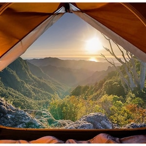 Può includere: Vista dall'interno di una tenda arancione, che si affaccia su una catena montuosa al tramonto. Il sole tramonta sul mare e le montagne sono coperte di alberi verdi. L'interno della tenda è visibile, con un sacco a pelo in basso.