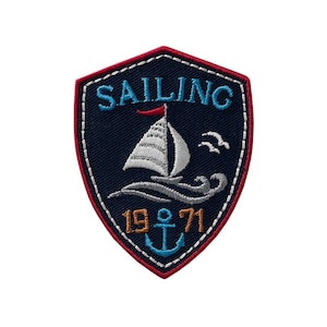 Op de afbeelding: Een blauwe en witte geborduurde patch met een zeilboot, golven en de tekst "SAILING 19 71" met een anker tussen de nummers.