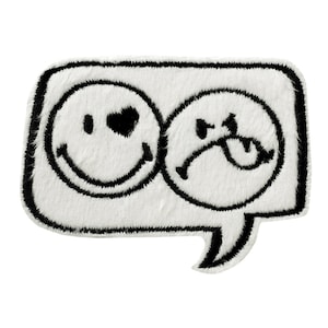 Pode incluir: Remendo de feltro branco com contorno preto em forma de balão de fala. Dentro do balão, há dois rostos sorridentes em preto e branco, um com um coração para o olho e o outro com uma carranca.