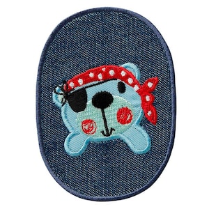 Könnte beinhalten: Ein blauer Jeans-Patch mit einem gestickten Comic-Bären, der ein rot-weiß gepunktetes Bandana und eine Augenklappe trägt. Der Bär hat eine schwarze Nase und rote Wangen.