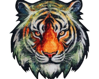 Op de afbeelding: Een stoffen embleem met een gedetailleerde illustratie van een tijgerkop. Het ontwerp toont levendige oranje, zwarte en gedempte groene tinten met een textuur. De tijger heeft doordringende amberkleurige ogen, een donkere neus en witte accenten.