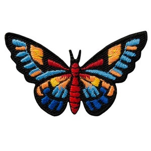 Op de afbeelding: Een kleurrijk geborduurd vlinderpatch met rode, oranje, gele, blauwe en zwarte accenten. De vlinder heeft een zwarte omtrek en is perfect om kleding, tassen of andere accessoires een vleugje whimsy te geven.