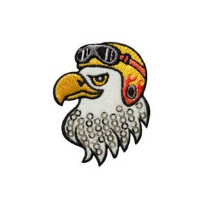 Könnte beinhalten: Ein gestickter Bügel-Patch mit einem weißen Weißkopfseeadler, der einen gelben Helm mit einem roten Flammenmuster und einer schwarzen Schutzbrille trägt. Die Federn des Adlers sind mit silbernen Pailletten bedeckt.