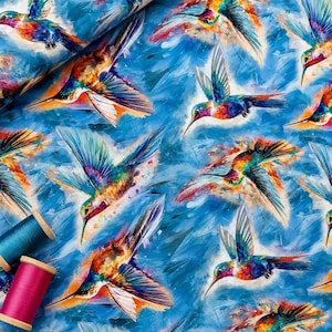 Peut inclure: Un tissu présentant un motif répétitif de colibris multicolores en vol sur un fond bleu texturé, accompagné de deux bobines de fil aux couleurs unies bleu sarcelle et magenta placées dans le coin inférieur gauche.