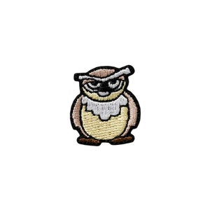 Op de afbeelding: Geborduurde strijkpatch van een bruine uil met witte ogen en een witte snavel. De uil draagt een bruine hoed met een witte rand.