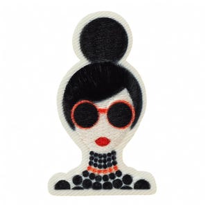 Könnte beinhalten: Ein gestickter Aufnäher mit einer stilisierten Figur mit hohem schwarzem Dutt, die eine runde, orange umrandete Sonnenbrille und rote Lippen trägt. Die Figur hat einen Kragen und ein Kleidungsstück im schwarzen Perlen-Look auf weißem Grund.