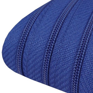 Könnte beinhalten: Nahaufnahme eines blauen Reißverschlussbandes mit drei Reihen von Zähnen. Das Band ist aus einem gewebten Stoff und hat eine strukturierte Oberfläche.