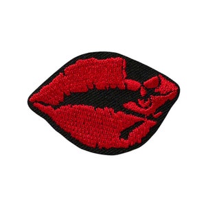 Könnte beinhalten: Rote gestickte Lippen auf einem schwarzen Stoff-Patch.