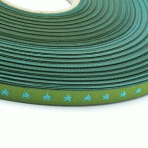 May include: A roll of green ribbon with a blue star pattern. The ribbon is wound tightly and the stars are visible on the edge of the roll.