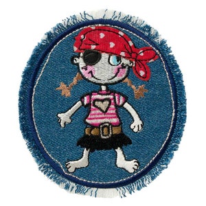 Può includere: Una toppa di denim blu con un bordo sfrangiato bianco, che presenta una ragazza dei cartoni animati ricamata con una bandana rossa e bianca, una camicia a righe rosa e bianca, una gonna nera e una benda sull'occhio.