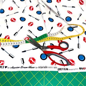 Nahaufnahme eines Kosmetik-Motivstoffs mit Lippen, Mascara, Pinseln und Lidschatten auf weißem Grund.