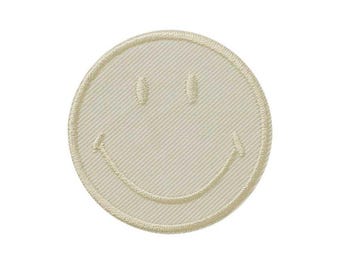 Op de afbeelding: Een ronde geborduurde patch in een effen crèmekleur met een gestikt smiley-gezicht. De patch heeft een duidelijke diagonale keperstructuur over het gehele oppervlak en een verhoogde, gestikte rand rondom de gehele omtrek.