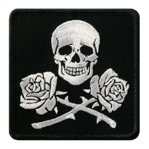 Könnte beinhalten: Schwarzer Stoff-Patch mit einem weißen gestickten Totenkopf und gekreuzten Knochen sowie zwei weißen Rosen.