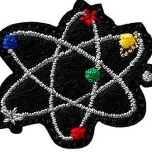Könnte beinhalten: Ein schwarzer gestickter Aufnäher, der ein Atom mit silbernem Umriss und fünf farbigen Kugeln darstellt: rot, blau, gelb, grün und rot.