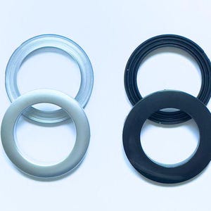 Può includere: Due set di anelli per tende, un set è argentato e l'altro è nero. Ogni set ha due anelli, uno più grande dell'altro.