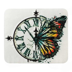 Puede incluir: Una esfera de reloj vintage con números romanos está agrietada y rota, con una mariposa colorida que emerge de las grietas. La mariposa tiene alas con tonos de azul, amarillo, naranja y rojo.