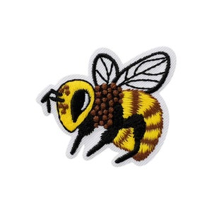 Op de afbeelding: Een geborduurde bij-patch in geel en bruin met zwarte vleugels. De bij vliegt met gespreide vleugels.