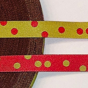 Op de afbeelding: Twee rollen lint met rode en gouden stippen. Het bovenste lint is goud met rode stippen en het onderste lint is rood met gouden stippen.