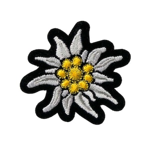 Op de afbeelding: Geborduurde patch met een edelweiss bloem ontwerp. De patch heeft witte bloemblaadjes, een gele kern en een zwarte rand. Deze bloemenpatch kan op kleding, tassen of andere stoffen artikelen worden gestreken of genaaid.