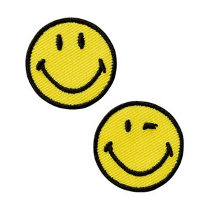 Könnte beinhalten: Zwei gelbe Smiley-Patches mit schwarzen Umrissen. Ein Smiley zwinkert.