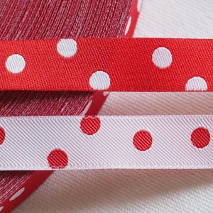 Op de afbeelding: Twee rollen lint met stippen. Het bovenste lint is rood met witte stippen. Het onderste lint is wit met rode stippen.