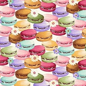 Op de afbeelding: Een herhalend patroon van kleurrijke macarons in verschillende tinten roze, groen, bruin, geel, paars en blauw. Sommige macarons zijn versierd met kleine witte bloemen. De achtergrond is licht crèmekleurig, wat een zoet en vrolijk ontwerp creëert.