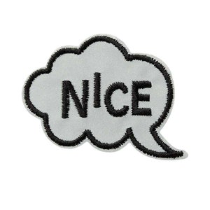 Op de afbeelding: Een strijkbare patch in de vorm van een spraakballon, met een witte achtergrond en een zwarte omtrek. Het woord "NICE" is in zwart geborduurd in de spraakballon.