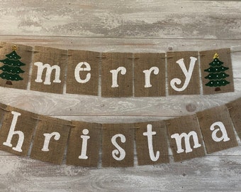 May include: A burlap banner with the words "merry christmas" in white letters. The banner is decorated with small green Christmas trees with gold stars.