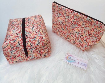 May include: Two fabric pouches featuring a dense floral pattern in shades of red, orange, yellow, and dark blue. Each pouch has a black zipper closure. A small rectangular business card with the text Made With Love is placed between them.