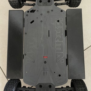 Peut inclure: Châssis noir pour une voiture télécommandée avec des jupes latérales noires et des roues noires. Le châssis porte l'inscription "ARRMA" et "SENTON".