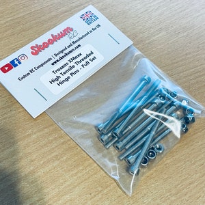 May include: A clear plastic bag containing a full set of silver high tensile threaded hinge pins for a Traxxas XMaxx RC car. The bag is labelled with the company name "Skookum RC" and the website address "www.skookumrc.com".