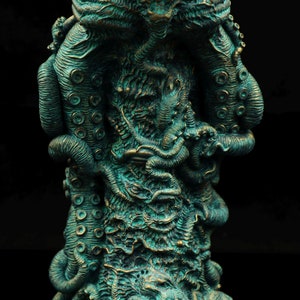 May include: A teal green and gold colored statue of a tentacled creature with a large head. The creature is depicted with many tentacles and a textured surface.