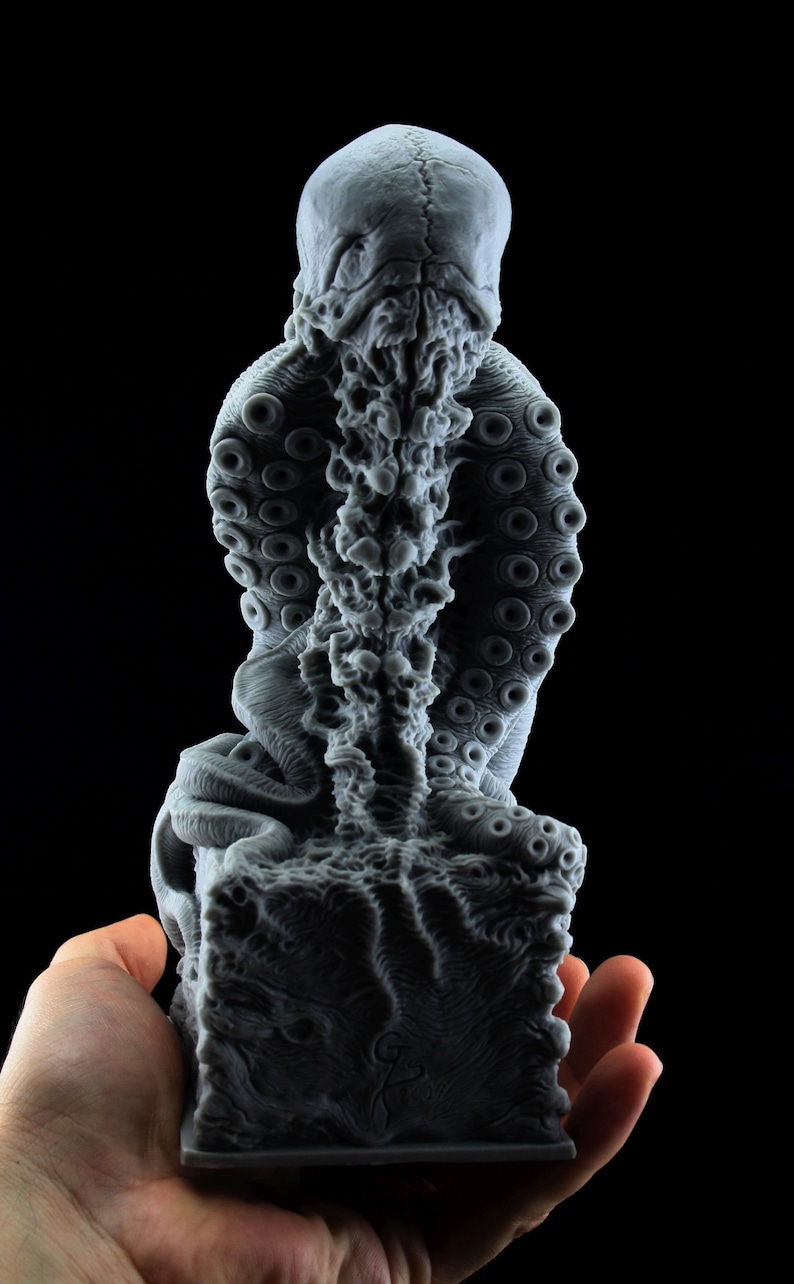 May include: A gray, detailed, 3D printed sculpture of a creature with a human-like head and an octopus-like body. The sculpture is sitting on a square base.