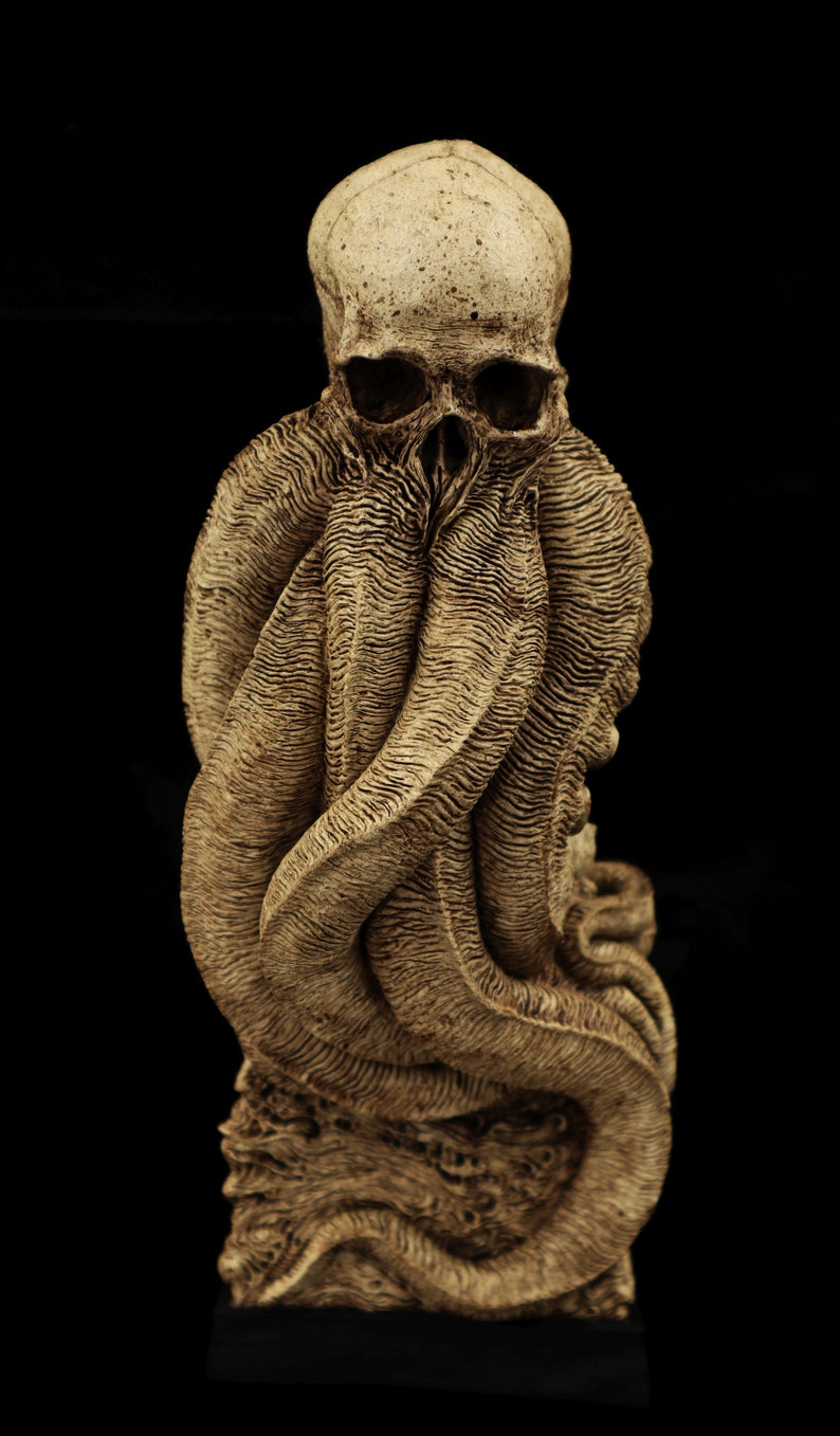 May include: A detailed sculpture of a skull with tentacles wrapped around it. The sculpture is made of a light brown material and has a textured surface.