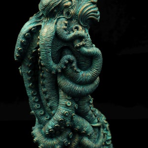 May include: A teal green, detailed, sculpted octopus figurine with multiple tentacles. The octopus is curled in on itself, with its head and eyes visible.