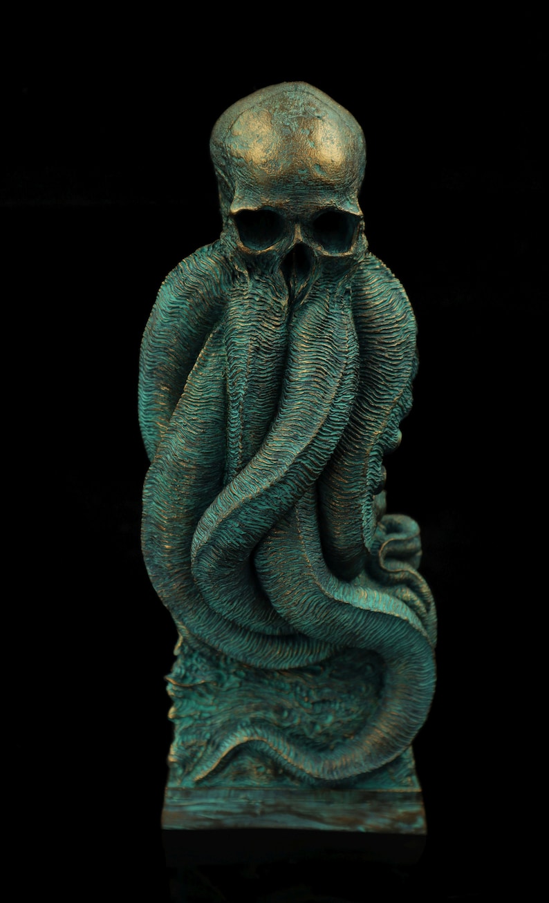 May include: A teal green and gold skull sculpture with tentacles wrapped around it. The sculpture is on a square base.