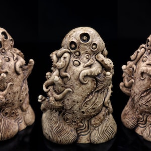 Könnte beinhalten: Eine detaillierte Keramikskulptur einer mehräugigen, tentakelartigen Kreatur mit einer strukturierten, organischen Oberfläche. Die Skulptur ist in Braun- und Weißtönen bemalt.