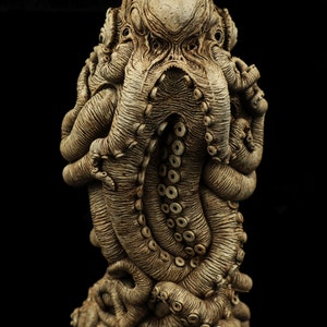 May include: A detailed ceramic sculpture of an octopus with a textured, aged appearance. The octopus is curled in on itself, with its tentacles intertwined. The sculpture is a dark brown color.