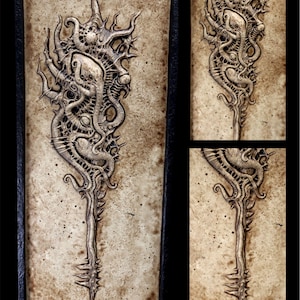 Puede incluir: Una serie de obras de arte en relieve enmarcadas, abstractas. La obra presenta un diseño orgánico complejo con una estructura central en forma de tallo y detalles intrincados y texturizados. La paleta de colores es principalmente neutra, con tonos beige y marrón.