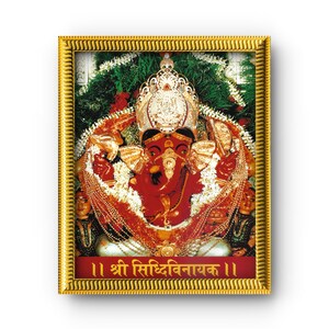 May include: A framed image of the Hindu deity Ganesha, depicted with a red complexion, adorned with gold jewelry and a crown. The image is set against a backdrop of green foliage and red flowers, with text in a foreign language at the bottom.