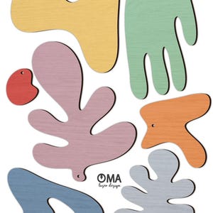 Puede incluir: Colección de recortes de madera coloridos en varias formas abstractas. Las formas incluyen un pez amarillo, una mano verde, un corazón rojo, una hoja rosa, una forma naranja, una forma azul y una forma gris. Cada recorte tiene un pequeño agujero para colgar. El logotipo "OMA laser design" es visible.
