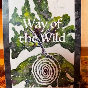 Puede incluir: Una carta de oráculo con una ilustración de acuarela. La carta presenta un árbol verde con el texto "Way of the Wild" y un diseño en espiral. La parte inferior de la carta dice "An Oracle Experience into the Irish Wisdom Tradition."
