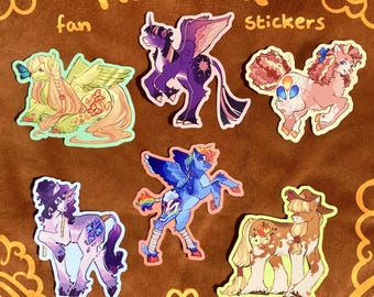 May include: A collection of six die-cut stickers featuring stylized pony characters. The text "Mane Six fan stickers" is printed at the top. The characters include a green pegasus, a purple alicorn, a pink pony, a white unicorn, a blue pegasus, and a brown earth pony.